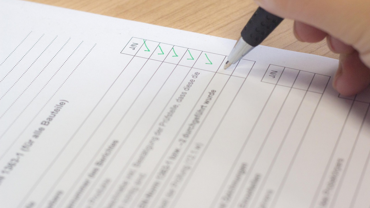 Hand mit einem Stift auf Blatt Papier und füllt eine Checkliste aus