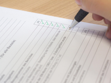 Hand mit einem Stift auf Blatt Papier und füllt eine Checkliste aus