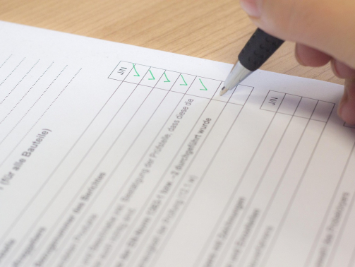 Hand mit einem Stift auf Blatt Papier und füllt eine Checkliste aus