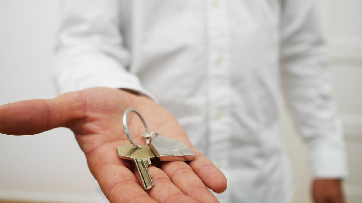 vorgehaltene Hand mit einem Schlüssel und Schlüsselanhänger, der ein Haus abbildet