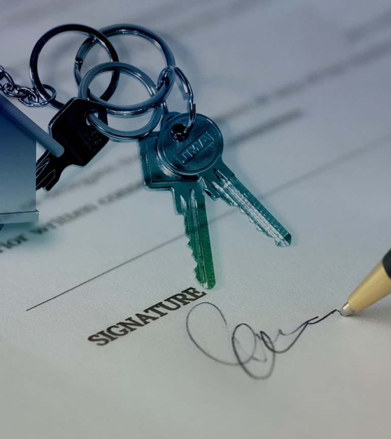 Unterschrift auf einem Blatt Papier und in linken oberen Ecke ein Haus mit Schlüssel