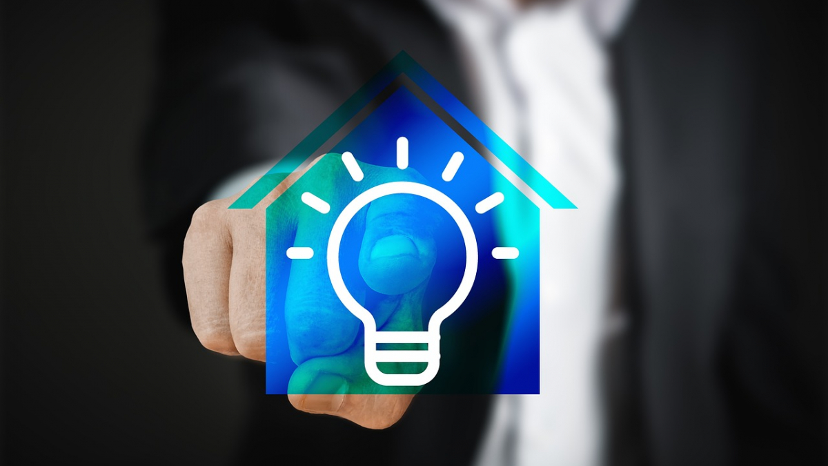 Hand klickt auf fiktives Haus mit Glühlampe