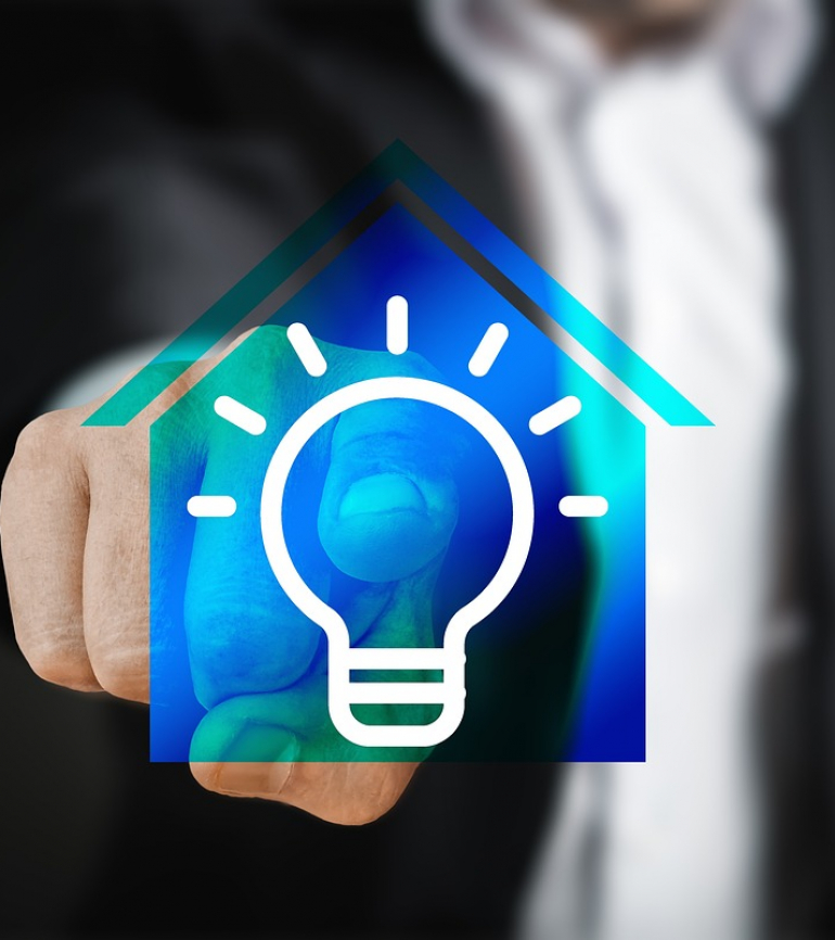 Hand klickt auf fiktives Haus mit Glühlampe